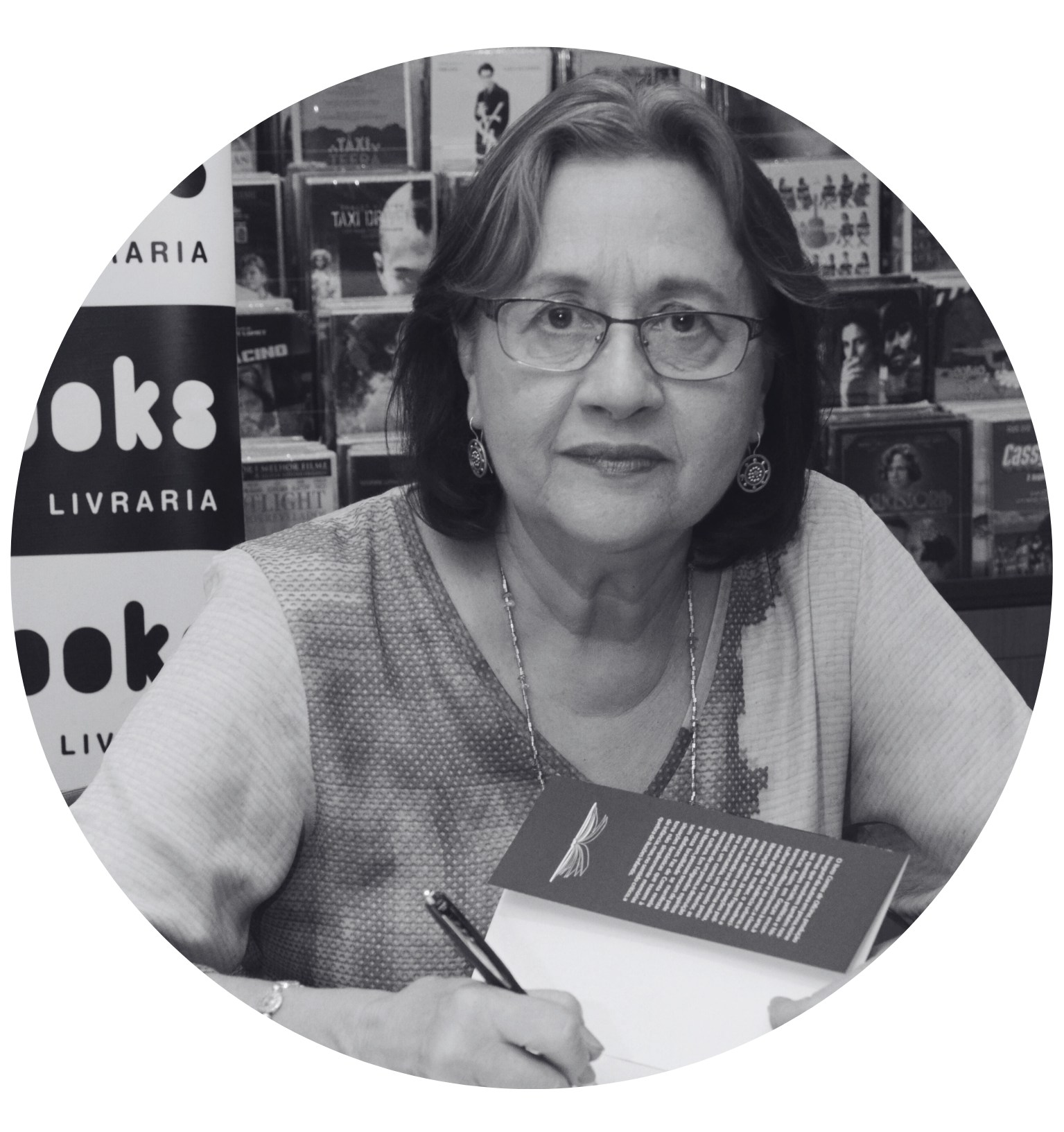 Imagem de Rute Gusmão em preto e branco com caneta assinando livro