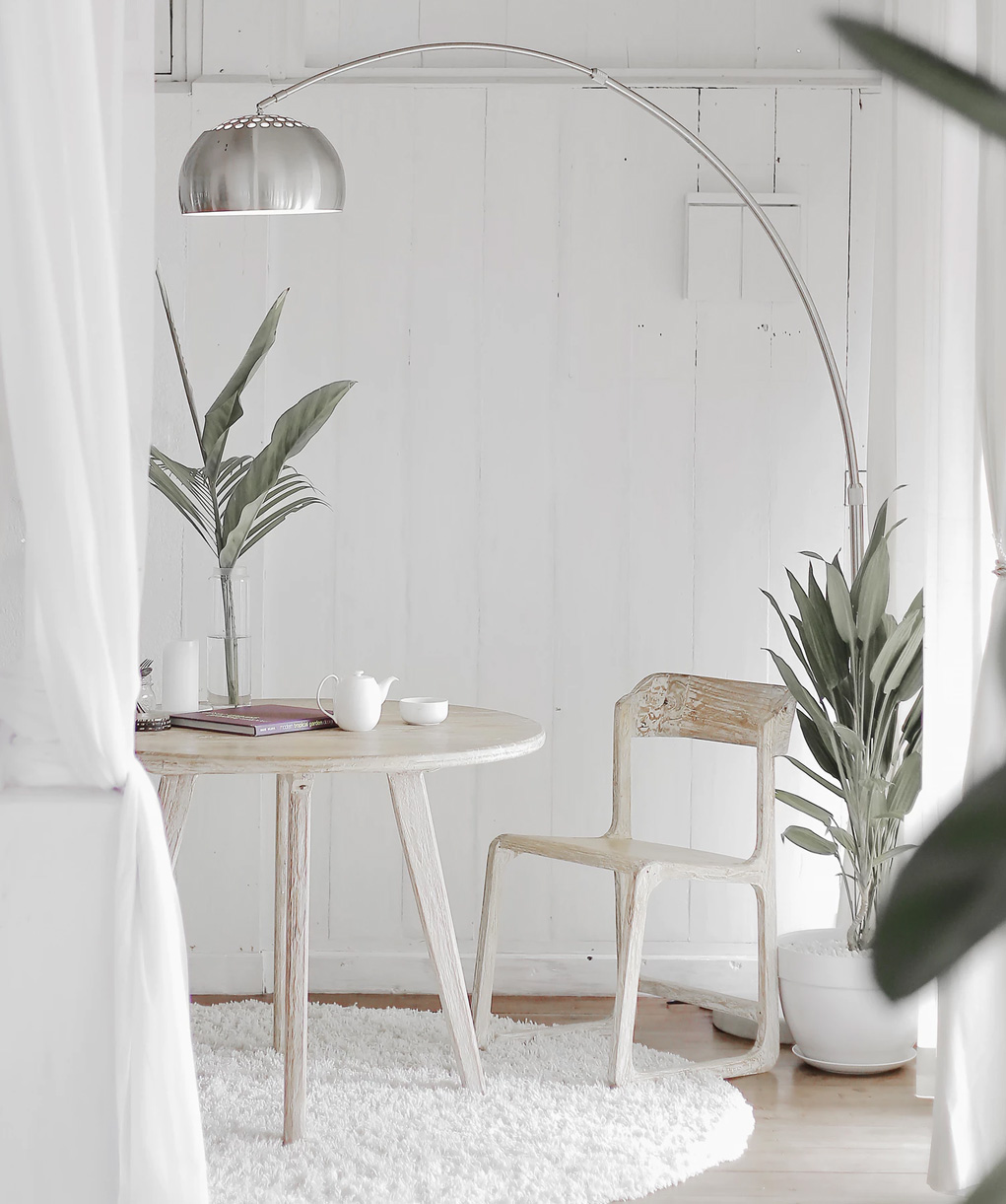 Cadeira de madeira em uma sala branca com objetos neutros